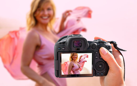 Photographer holding digital camera in hand and taking picture of fashion model