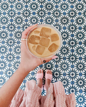 hand holding a cup of iced coffee with blue tiles lifestyle