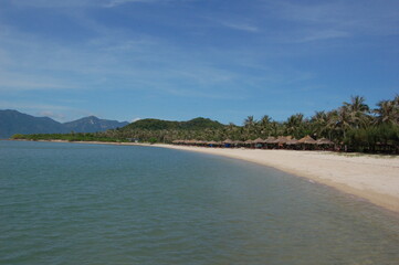 View of the beach with palm trees and calm sea on a tropical island.