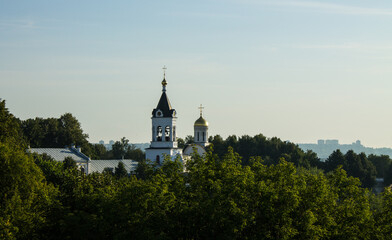 Fototapeta na wymiar The bell tower of the Theotokos-Rozhdestvensky monastery among the lush green foliage of trees on a sunny summer day in Vladimir russia