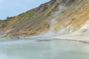 hot mineralized lake with thermal spring and smoking fumaroles in the caldera of the Golovnin volcano on the island of Kunashir