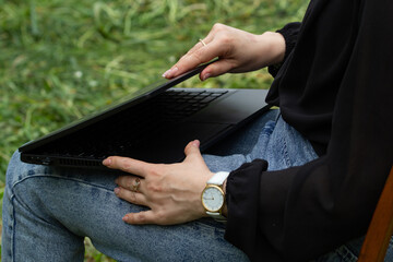 women's hands open a laptop, on the street, time to work, clock on hand, outdoors, the beginning of the working day, free schedule,