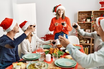 Group of young people smiling happy celebrating christmas toasting with wine at home.