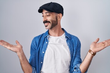 Hispanic man with beard standing over isolated background smiling showing both hands open palms,...