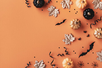 Halloween holiday background with party decorations of pumpkins, bats, spiders on orange top view. Happy halloween card in flat lay style.