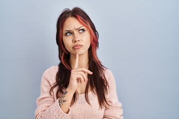 Young caucasian woman wearing pink sweater over isolated background thinking concentrated about doubt with finger on chin and looking up wondering