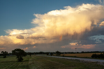 heavy clouds with a rainbow float over the landscape