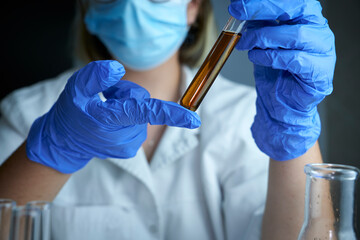 A young scientist looking pensively at tubing with liquid. Lab assistant hands Erlenmeyer flask...
