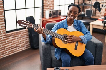 African american woman musician playing classical guitar at music studio