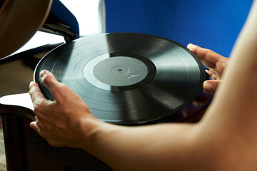Young woman holding vinyl record over wooden record player. Beautiful girl in vintage dress wants...