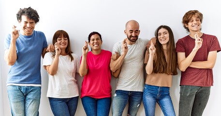 Group of young friends standing together over isolated background gesturing finger crossed smiling with hope and eyes closed. luck and superstitious concept.