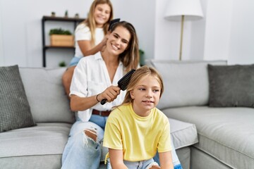 Mother and daughters smiling confident combing hair at home