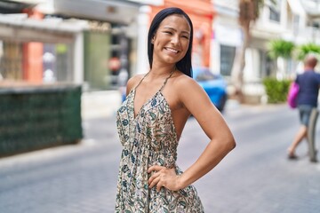 Young beautiful latin woman smiling confident looking to the side at street