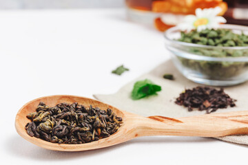 Fresh harvest of tea leaves on white background, top view, copy space. Assortment or variety tea leaves, Afternoon tea concept, desserts for tea, warming drink during low season.