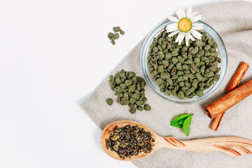 Fresh harvest of tea leaves on white background, top view, copy space. Assortment or variety tea leaves, Afternoon tea concept, desserts for tea, warming drink during low season.