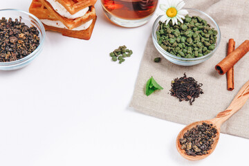 Fresh harvest of tea leaves on white background, top view, copy space. Assortment or variety tea leaves, Afternoon tea concept, desserts for tea, warming drink during low season.