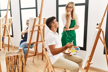 Art woman teacher with serious expression looking draw of paint student at studio.