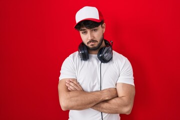 Hispanic man with beard wearing gamer hat and headphones looking sleepy and tired, exhausted for fatigue and hangover, lazy eyes in the morning. © Krakenimages.com