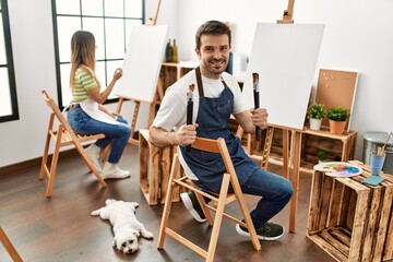 Two hispanic students smiling happy painting at art studio