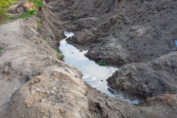 puddle at the bottom of the excavated pit near the fence