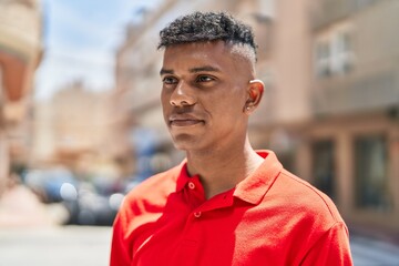 Obraz premium Young latin man looking to the side with relaxed expression at street
