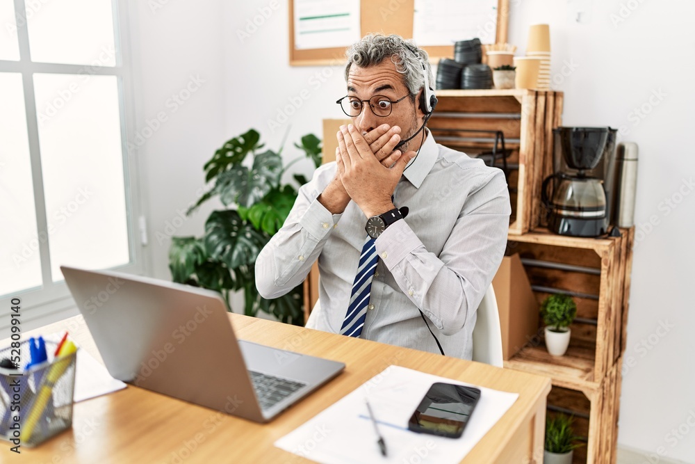 Canvas Prints Middle age hispanic business man working at the office wearing operator headset shocked covering mouth with hands for mistake. secret concept.