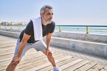 Middle age hispanic man wearing sportswear resting at seaside