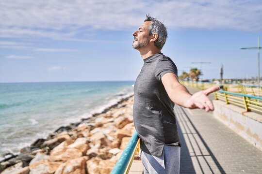 Middle age hispanic man wearing sportswear breathing at seaside