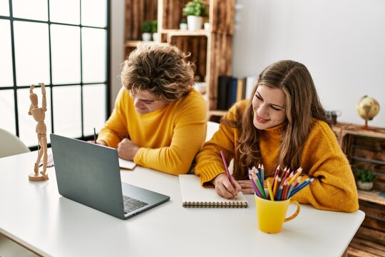 Young caucasian couple smiling confident having online art class at home