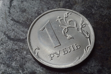 Russian coin with a face value of 1 ruble lies on a dark metal surface. close-up
