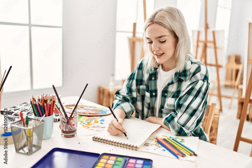 Sticker young artist student girl smiling happy painting sitting on desk at art studio.