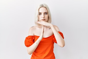 Young caucasian woman standing over isolated background doing time out gesture with hands,...