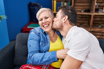 Obraz premium Mother and son sitting on sofa kissing at home