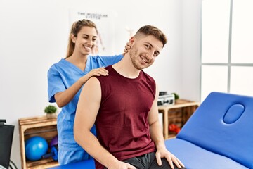 Obraz premium Young hispanic physioterapist woman make neck rehab treatment to man at the clinic.