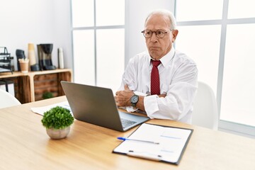 Senior man working at the office using computer laptop skeptic and nervous, disapproving expression...