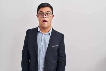 Young hispanic man with down syndrome wearing business style afraid and shocked with surprise expression, fear and excited face.