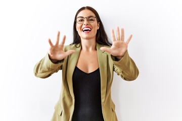 Young brunette woman standing over isolated background showing and pointing up with fingers number...