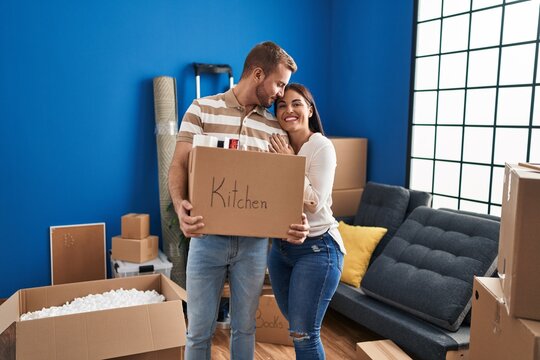 Man and woman couple hugging each other holding kitchen package standing at new home