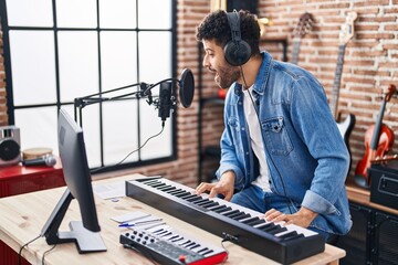 Young arab man musician singing song playing piano keyboard at music studio