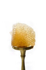 Close-up of light transparent honeycombs on a golden stand on a white background. Natural honey and wax