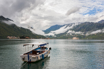 Fototapeta na wymiar The Bay of Kotor (Boka Kotorska) from the little town of Perast, Montenegro, on a cloudy day, with a motor launch moored in the foreground