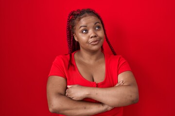 African american woman with braided hair standing over red background smiling looking to the side and staring away thinking.