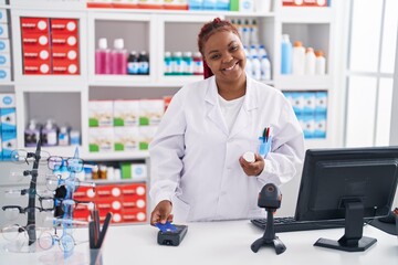 African american woman pharmacist using credit card and data phone at pharmacy