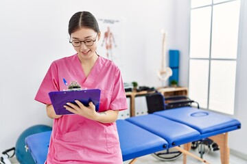 Obraz premium Young asian woman using clipboard at physiotherapy clinic