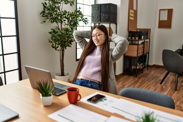 Young chinese businesswoman smiling happy relaxing with hands on head at the office.