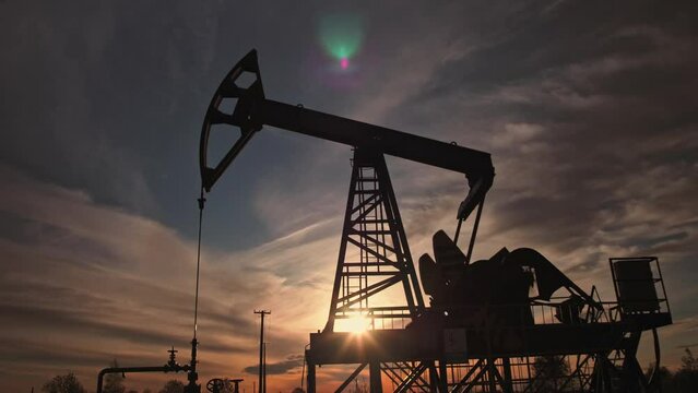 Low Angle Shot Of Working Oil Pump From Oil Field At Sunset Background. The Industrial Equipment. Oil Industry, Crude Oil Prices Concept.