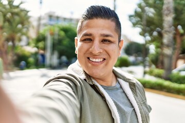Young latin man smiling happy make selfie by the camera at the city.