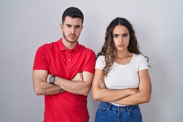 Fototapeta premium Young hispanic couple standing over isolated background skeptic and nervous, disapproving expression on face with crossed arms. negative person.