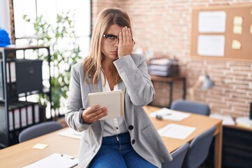 Young hispanic woman working at the office wearing glasses yawning tired covering half face, eye and mouth with hand. face hurts in pain.