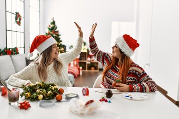 Woman couple making handmade christmas decoration high five raised up hands at home